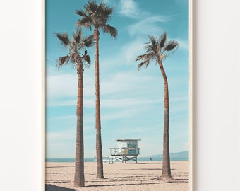 May include: A framed photograph of a beach scene with three palm trees and a lifeguard stand in the distance. The sky is blue and the sand is white.