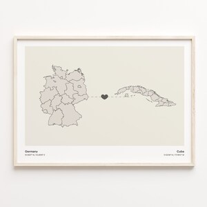 May include: A map print with a black heart connecting Germany and Cuba. The map shows the outlines of each country. The text below the map reads "Germany 50.1157° N / 10.4515° E" and "Cuba 21.5218° N / 77.7812° W".