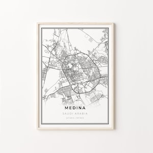 Può includere: Una stampa incorniciata in bianco e nero della mappa di Medina, Arabia Saudita. La mappa della città presenta una planimetria stradale dettagliata con il nome della città e le coordinate in basso. La stampa è in una cornice di legno chiaro.