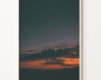 May include: A photograph of a dark sky with a crescent moon and a layer of orange clouds at the horizon.