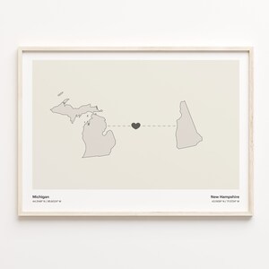 May include: A print of a map showing the states of Michigan and New Hampshire connected by a dashed line with a black heart in the middle. The text "Michigan 44.3148° N / 85.6023° W" is below the state of Michigan and the text "New Hampshire 43.1809° N / 71.5724° W" is below the state of New Hampshire.
