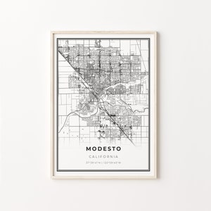 May include: A framed black and white map print of Modesto, California. The map details the city's layout with streets and landmarks. The city name and state are printed below the map, along with the coordinates 37°39'41"N | 120°59'40"W.