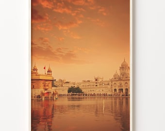 May include: A golden temple with a white dome and a reflecting pool in front of it. The sky is a vibrant orange colour, suggesting a sunset.