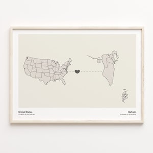 May include: A map print with a black heart connecting the United States and Bahrain. The coordinates for each country are listed below the map. The map is framed in a light wood frame.