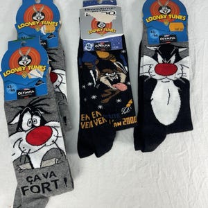 May include: Three pairs of Looney Tunes character socks. One pair is black with a design of Wile E. Coyote and the Road Runner. The other two pairs are grey and black with Sylvester the Cat. Each pair has a tag with the Looney Tunes logo.