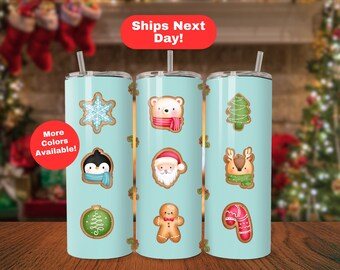 May include: Three stainless steel tumblers with lids and straws. Each tumbler features a different Christmas-themed design with a blue background and brown accents. The designs include a snowflake, a penguin, an ornament, a bear, Santa Claus, a reindeer, a Christmas tree, a gingerbread man, and a candy cane.