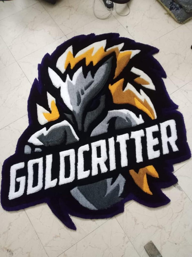 May include: A purple, black, white and yellow rug with a stylised creature and the text "GOLDCRITTER" in white.