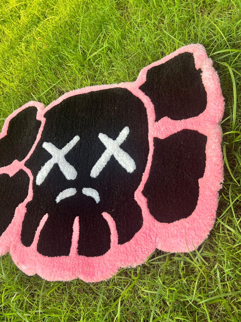 May include: A pink and black rug with a cartoon face with two X's for eyes and a frown.