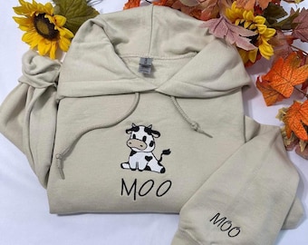 Kuh bestickter Hoodie; Sitzende Kuh mit MOO gestickt auf der Manschette des Hoodie, Herbst Hoodies