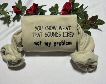 Może przedstawiać: Beżowa bluza z haftem "YOU KNOW WHAT THAT SOUNDS LIKE? not my problem" w kolorze czarnym.