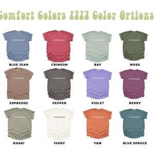 May include: A display of Comfort Colors 1717 t-shirts in various colors, including blue jean, crimson, bay, moss, espresso, pepper, violet, berry, khaki, ivory, yam, and blue spruce. Each shirt has the word "overstimulated" printed on it.