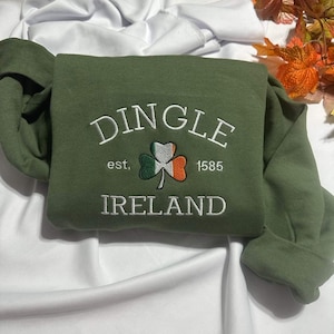 May include: A green sweatshirt with white embroidery that reads "Dingle est. 1585 Ireland". The embroidery also includes a green shamrock with orange and white accents.
