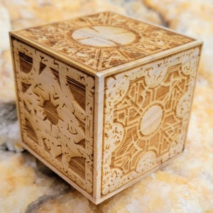 May include: A wooden box with intricate carvings on all sides. The top of the box has a large, circular design in the center.