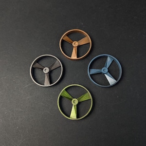 以下が含まれることがあります： 4つの小さな丸い金属製のスピナーが、銅、グレー、青、緑の異なる色で表示されています。各スピナーには3つのブレードがあります。