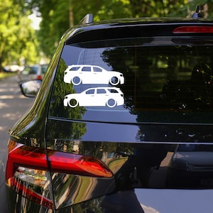May include: Two white car decals are displayed on the rear window of a black vehicle. The decals depict a side profile of a station wagon with large circular wheels. The car decals are a simple, minimalist design.