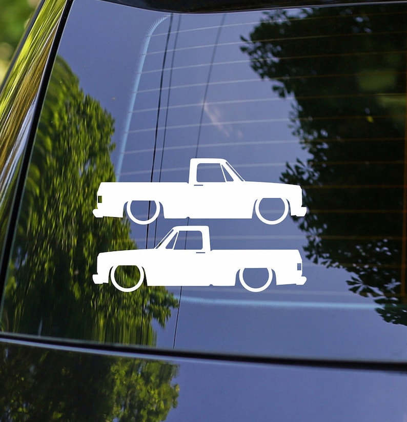 Puede incluir: Dos calcoman&iacute;as de silueta blanca de una camioneta pick-up con una cama larga. Las camionetas est&aacute;n mirando hacia el lado derecho de la imagen. Las calcoman&iacute;as est&aacute;n sobre un fondo azul.