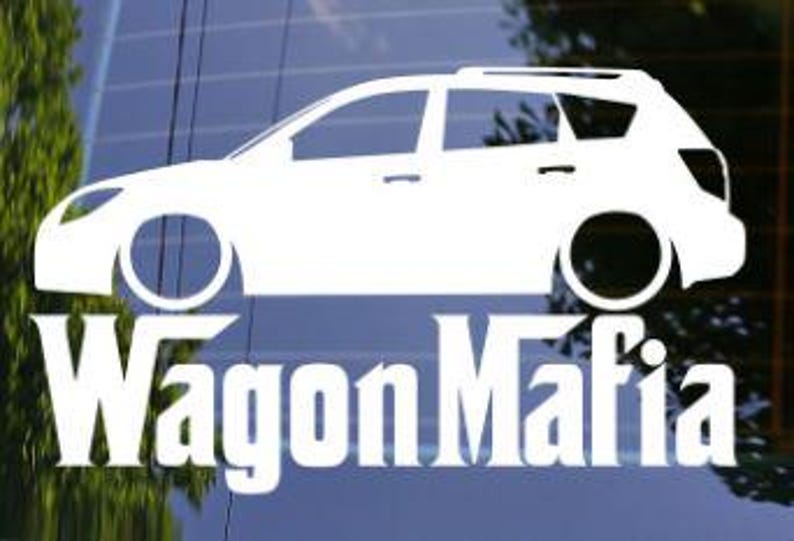 May include: White vinyl decal of a station wagon with the text "Wagon Mafia" underneath. The car graphic is a side profile, showing the wheels and windows. The decal is displayed on a window.