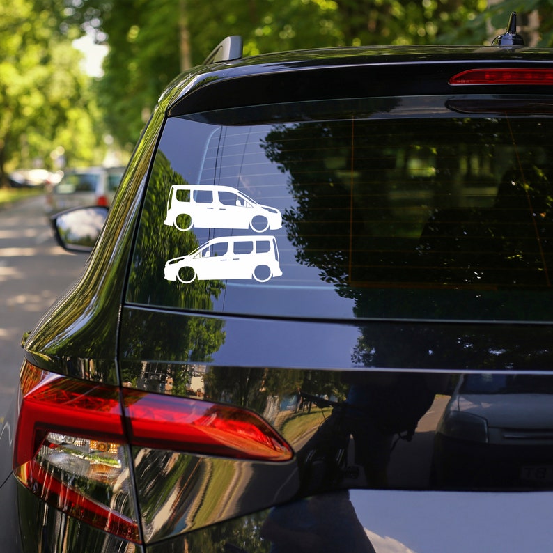 May include: A black car with a rear window sticker featuring two white silhouettes of vans. The vans are side-by-side, with the top van slightly larger than the bottom van.