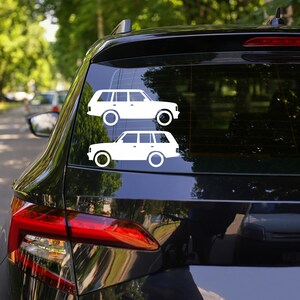 May include: Two white car decals are affixed to the rear window of a black vehicle. The decals depict a side profile of a station wagon. The car decals are a simple, minimalist design.