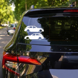 May include: Two white car decals are affixed to the rear window of a black car. The decals are side profile illustrations of a car, featuring circular wheel designs. The car decals are arranged one above the other.