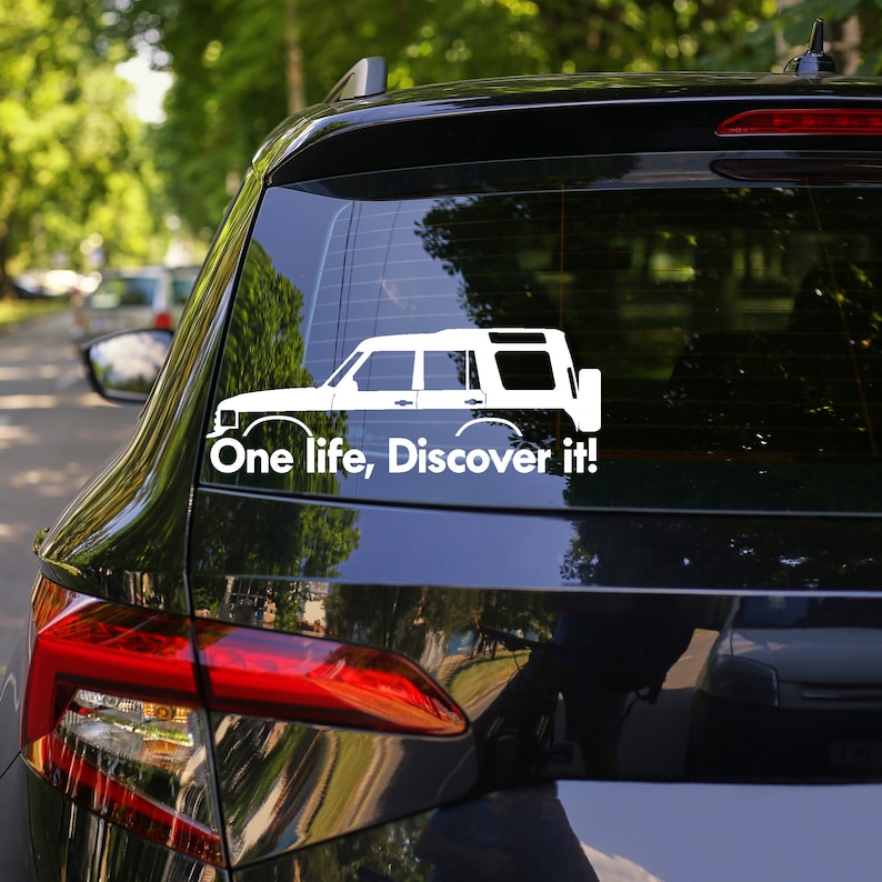 Peut inclure: Autocollant en vinyle blanc repr&eacute;sentant la silhouette d'un Land Rover Discovery avec le texte "One life, Discover it!" sur une voiture noire.