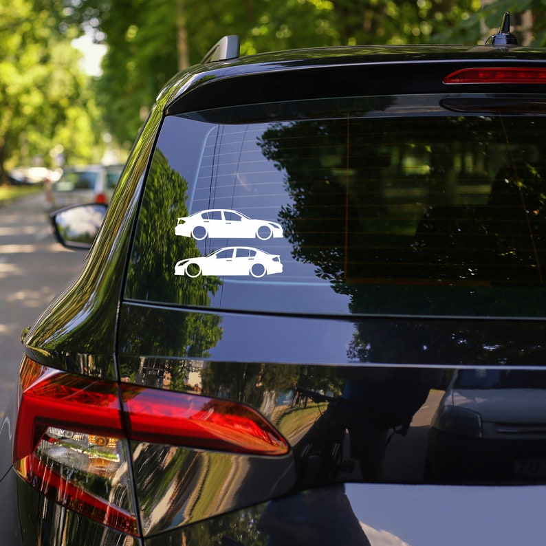 Peut inclure: Une voiture noire avec une silhouette blanche de deux voitures sur la vitre arri&egrave;re. La silhouette des voitures est un autocollant.