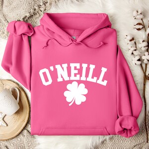 May include: Pink hoodie with a white graphic of a four-leaf clover and the text "O'NEILL" in a collegiate font.
