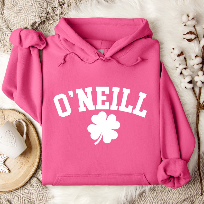 May include: Pink hoodie with a white graphic of a four-leaf clover and the text "O'NEILL" in a collegiate font.
