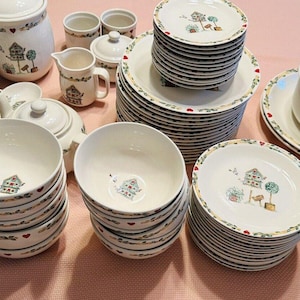 May include: A set of white ceramic dishes with a birdhouse and floral design. The set includes bowls, plates, mugs, and a teapot.