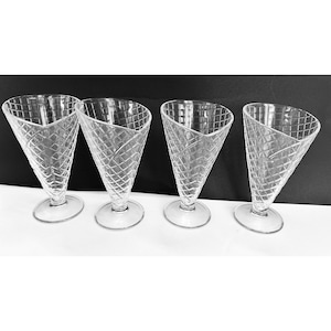 Puede incluir: Cuatro copas de postre de vidrio transparente en forma de cono de helado. Las copas tienen un patrón de cono de waffle y una base ancha.