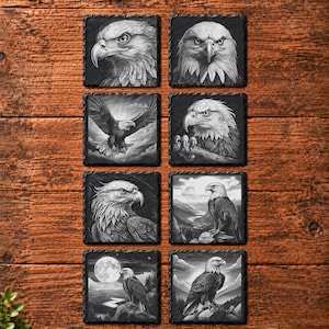 May include: A set of eight square black slate coasters, each featuring a detailed monochrome illustration of a bald eagle. The designs include close-up portraits, eagles in flight, and eagles perched in mountainous landscapes under a full moon.