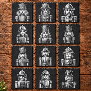 May include: A set of twelve square black slate coasters, each featuring a detailed white line art illustration of a unique nutcracker figure in a military-style uniform with various hats, arranged in a grid pattern on a wooden surface.