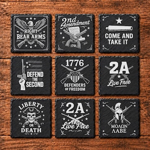 May include: A set of nine square black slate coasters featuring white engraved designs related to the Second Amendment, including text like The Right to Bear Arms, 2nd Amendment, Come and Take It, Defend the Second, 1776, 2A Live Free, Liberty or Death, and Molon Labe.
