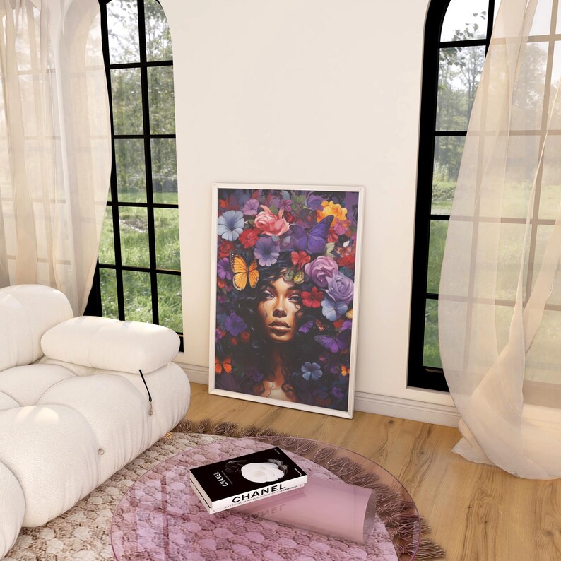 K&ouml;nnte beinhalten: Ein gerahmter Kunstdruck mit einer Frau mit Blumenkrone und Schmetterlingen. Das Kunstwerk zeigt eine lebendige Mischung aus Farben, darunter Rosa, Lila und Blau. Ein Buch mit dem Wort "CHANEL" liegt auf einem runden Teppich.
