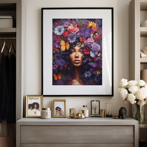 K&ouml;nnte beinhalten: Ein gerahmter Kunstdruck mit einer Frau mit Blumenschmuck und Schmetterlingen. Das Kunstwerk befindet sich in einem schwarzen Rahmen und wird auf einer grauen Kommode ausgestellt. Weitere Gegenst&auml;nde auf der Kommode sind gerahmte Fotos, Kerzen und dekorative Objekte.