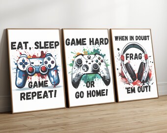 May include: Three framed art prints with gaming themes. The prints feature a blue and red game controller, a black and white game controller, and a pair of headphones. Each print has a different gaming quote in black text on a white background.