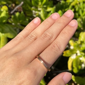 May include: A simple gold band ring worn on a finger.