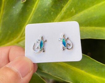 May include: A pair of silver earrings featuring a green and blue opal lizard design.