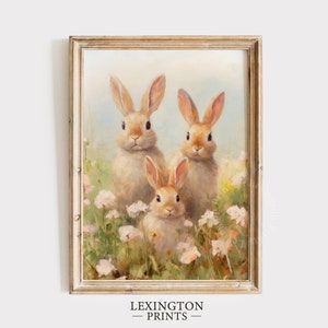 May include: A framed print featuring three rabbits amidst a field of wildflowers. The rabbits have light brown fur and long ears. The artwork has a soft, pastel color palette with a gold-colored frame. The text "LEXINGTON PRINTS" is at the bottom.