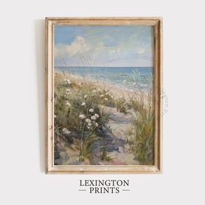Puede incluir: Una pintura enmarcada de una escena de playa con un camino que conduce a través de hierba alta y flores blancas hasta el océano. El cielo es azul con nubes blancas y el agua es azul claro.