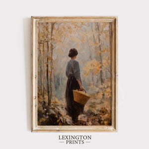 Könnte beinhalten: Ein gerahmter Vintage-Druck zeigt eine Frau in einem langen Kleid, die durch einen Wald geht und einen Korb trägt. Das Kunstwerk weist eine gedämpfte Farbpalette aus Braun-, Grün- und Gelbtönen auf, mit dem Text "LEXINGTON PRINTS" unten.