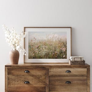 Vintage Spring wall art wildflower field landscape painting art print displayed in an antique frame, featuring pink and beige wildflowers up close. This Spring decor can also be Easter decor. The painting features intricate brushwork and colors. The shop name Lexington Prints is written below.
