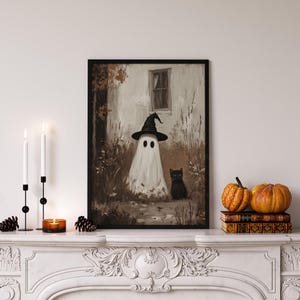 Vintage Halloween wall art print of a cute white ghost dressed as a witch in a witch hat next to his cute black cat in a fall scene. The Halloween painting features moody fall colors of black, white and brown hues along with intricate brushwork. The artwork embodies themes of vintage Halloween wall decor, dark farmhouse decor, dark cottagecore decor, gothic decor, and halloween wall decor. The shop name Lexington Prints is written below
