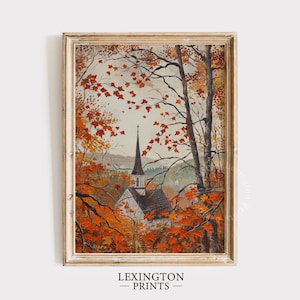 May include: Framed art print of a church with a tall steeple, surrounded by trees with vibrant orange and red autumn leaves. The artwork is set in a gold-colored frame. The text "LEXINGTON PRINTS" is at the bottom.