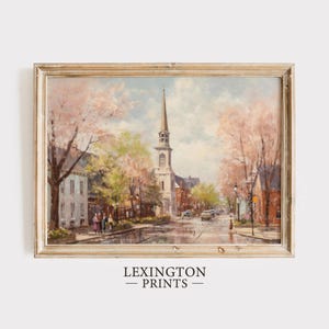 May include: A framed painting depicting a quaint town square with a church steeple in the center. The scene is bathed in warm sunlight, with blooming trees lining the streets. The painting is set against a light blue sky with fluffy white clouds.