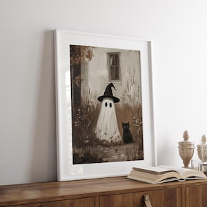 Vintage Halloween wall art print of a cute white ghost dressed as a witch in a witch hat next to his cute black cat in a fall scene. The Halloween painting features moody fall colors of black, white and brown hues along with intricate brushwork. The artwork embodies themes of vintage Halloween wall decor, dark farmhouse decor, dark cottagecore decor, gothic decor, and halloween wall decor. The shop name Lexington Prints is written below