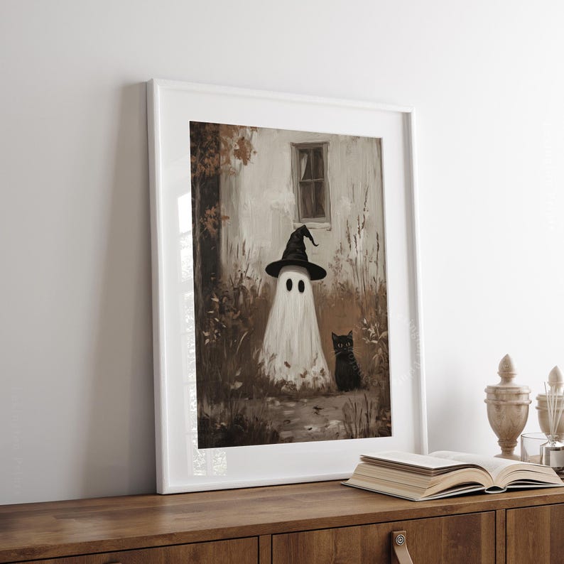 Vintage Halloween wall art print of a cute white ghost dressed as a witch in a witch hat next to his cute black cat in a fall scene. The Halloween painting features moody fall colors of black, white and brown hues along with intricate brushwork. The artwork embodies themes of vintage Halloween wall decor, dark farmhouse decor, dark cottagecore decor, gothic decor, and halloween wall decor. The shop name Lexington Prints is written below