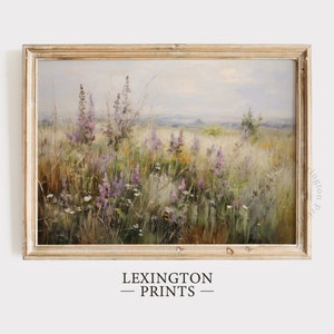 May include: A framed painting depicting a field of wildflowers in shades of purple, pink, and white. The field is set against a hazy blue sky and a distant horizon. The painting is in a light wood frame.