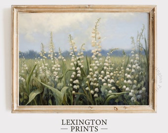 May include: A framed painting of a field of white lily of the valley flowers with green leaves against a blue sky with white clouds. The painting is in a light wood frame.