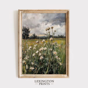 Pode incluir: Pintura de paisagem emoldurada que retrata um campo de flores silvestres brancas sob um céu nublado. A obra de arte, com uma estética vintage, apresenta uma moldura dourada e o texto "LEXINGTON PRINTS" na parte inferior.